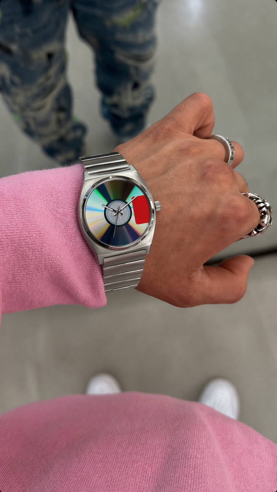 Person wearing a watch with a colorful face on a plain background